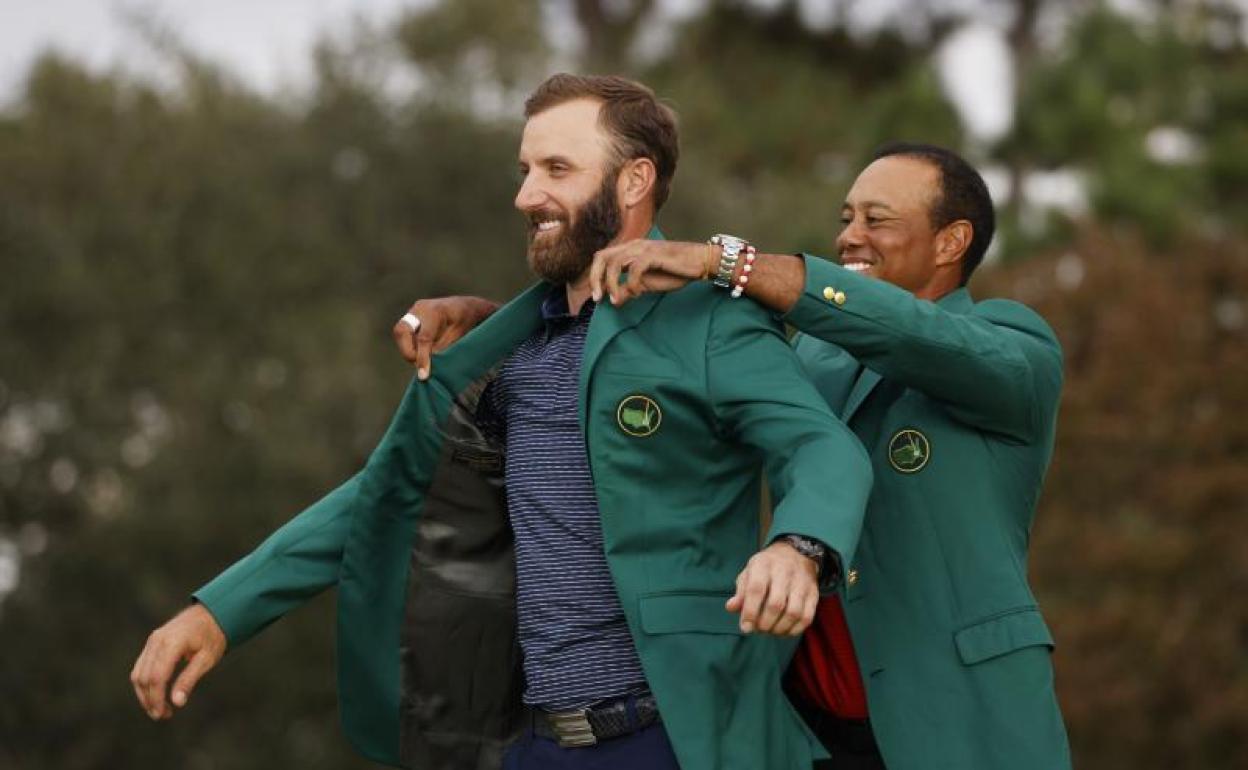 Tiger Woods enfunda a Dustin Johnson la chaqueta verde de campeón del Masters de Augusta. 