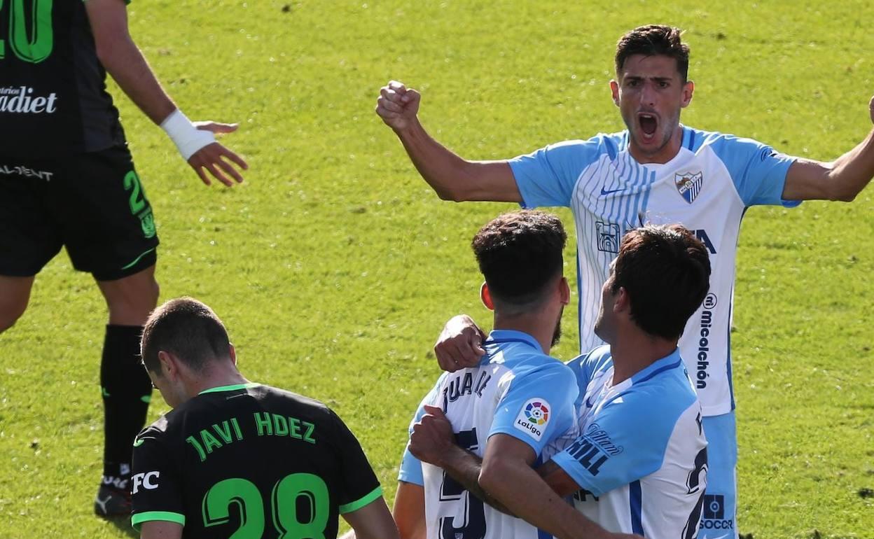 Juande es abrazado por Escassi tras marcar el gol del Málaga, con Chavarría acercándose al fondo. 