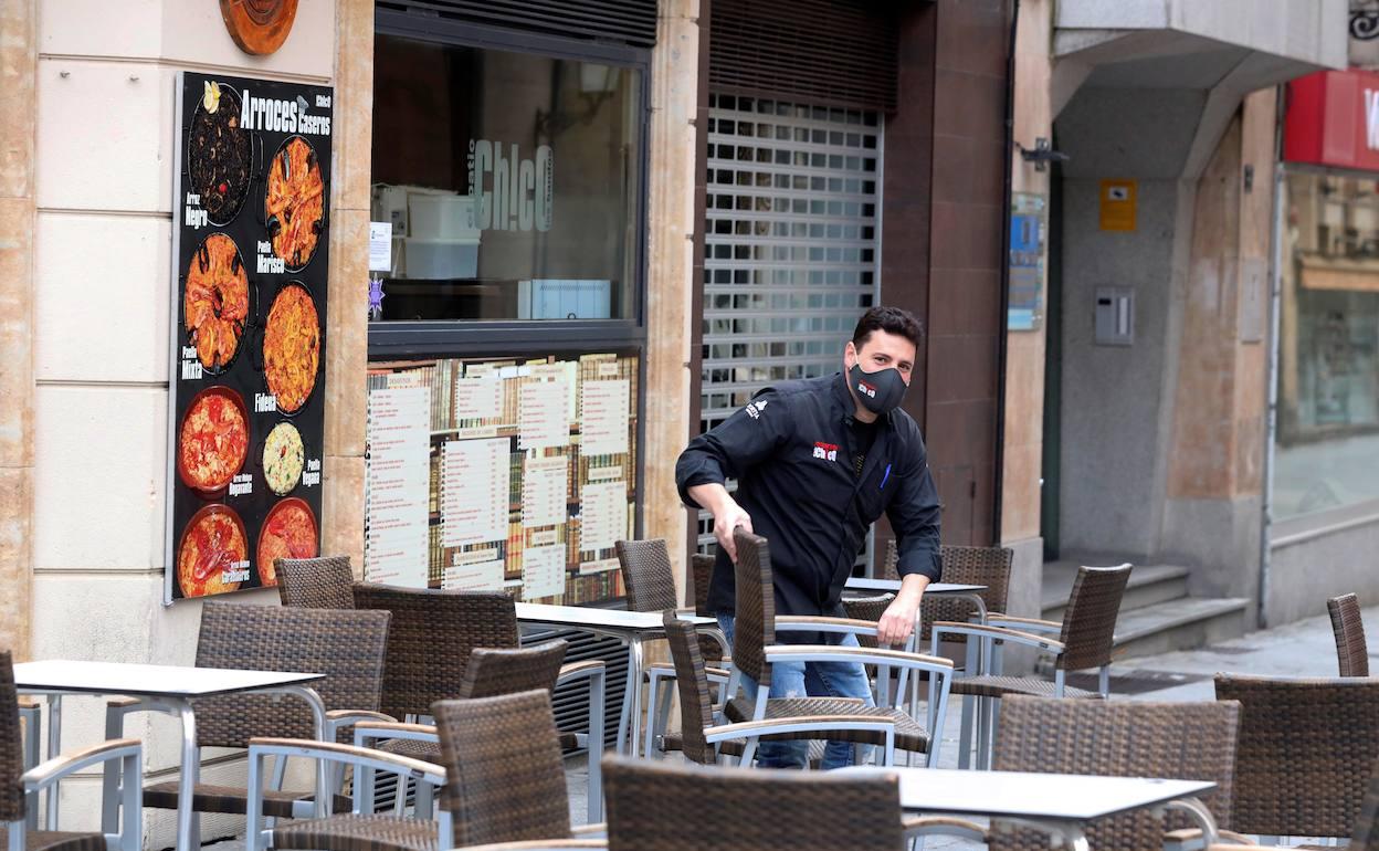Un camarero monta la terraza de un restaurante. 