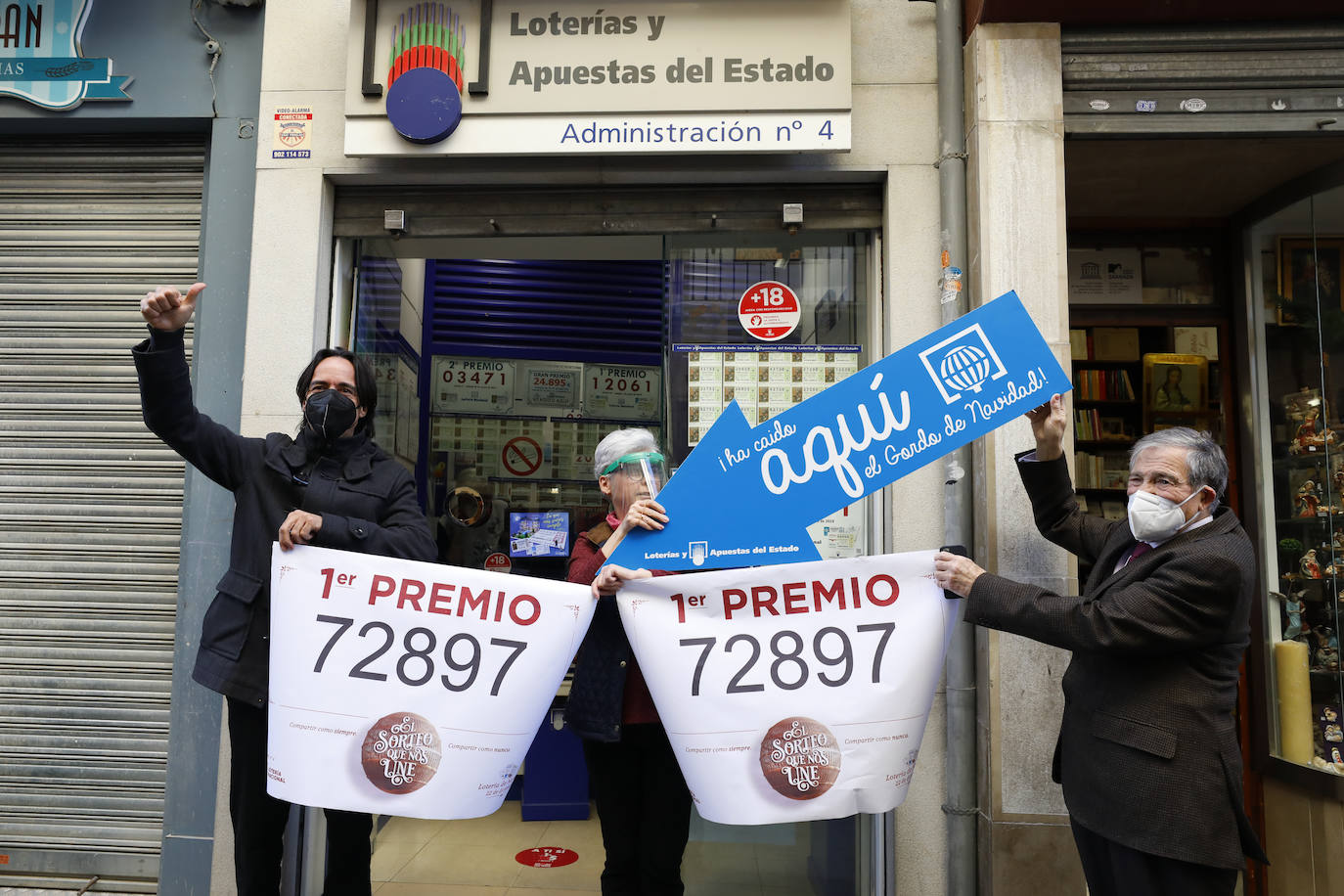 Loteros posan en la administración de lotería situada en la calle Principe 11, en Granada, en la que se ha repartido parte del número '72897´ correspondiente a 'El Gordo' de la Lotería de Navidad