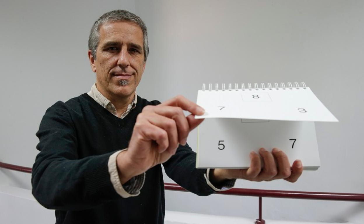 Javier García posa con un libro que se utiliza para enseñar el valor de los números a los alumnos de primaria. 