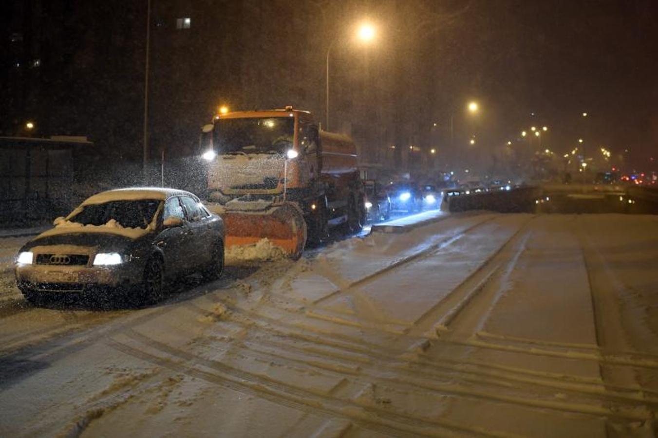 Una quitanieves trabaja mientras los vehículos circulan lentamente en Madrid debido a la fuerte tormenta de nieve.