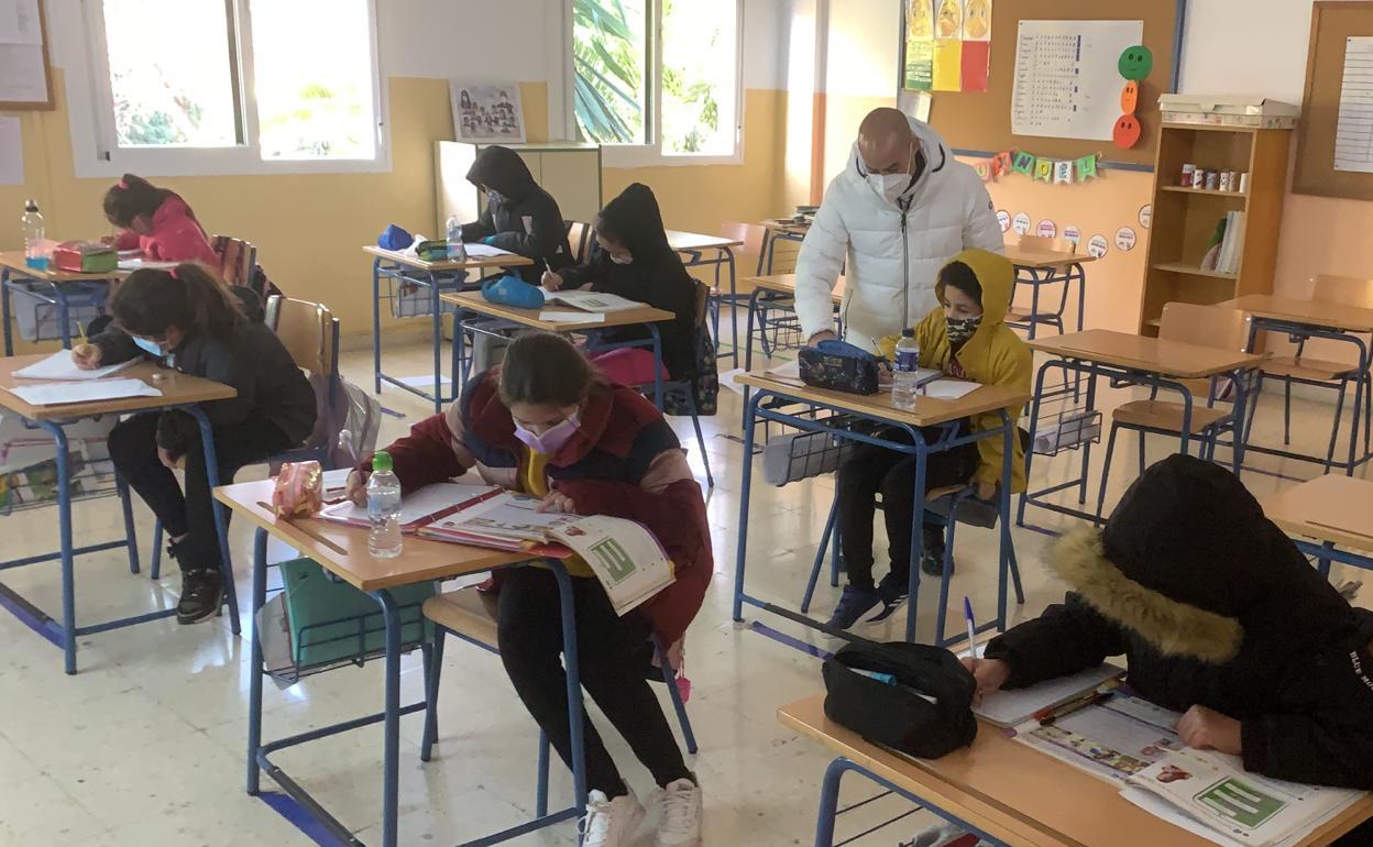 Una clase del colegio Manuel Altolaguirre de Málaga capital, con alumnos y profesor con abrigos. 