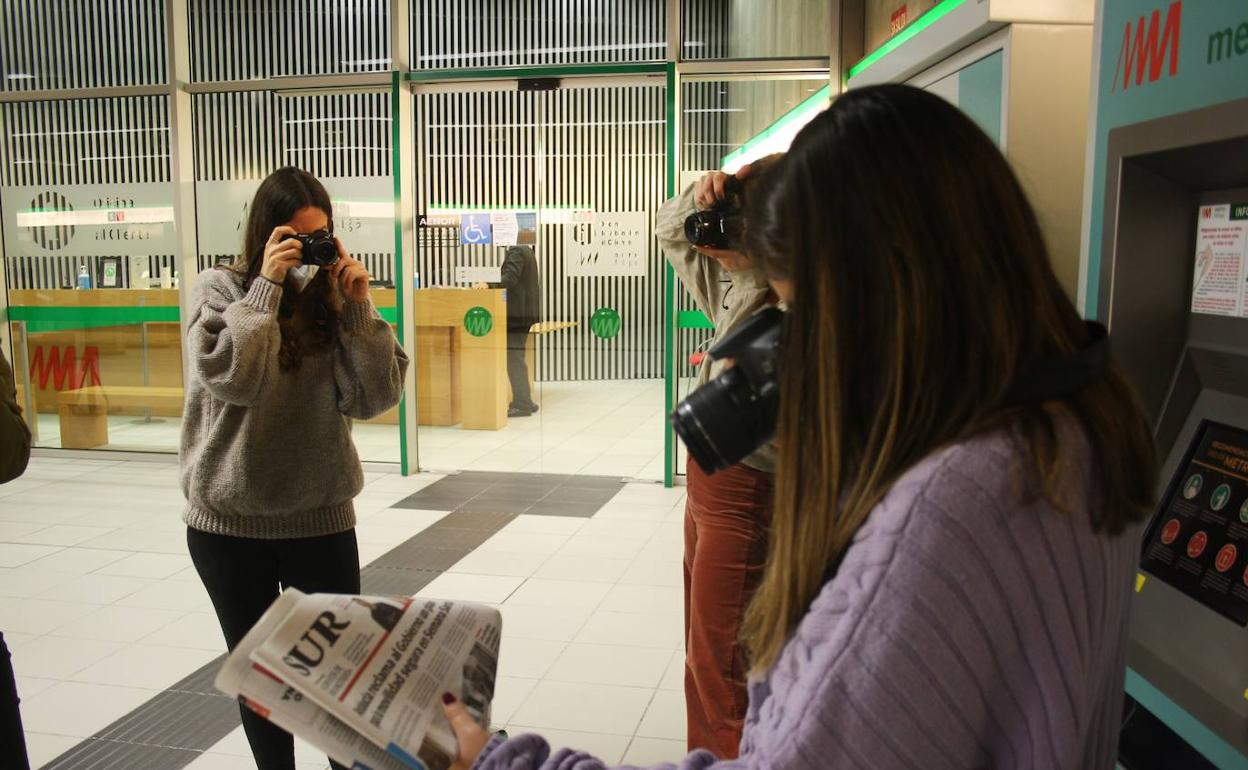 Una de las chicas comienza las fotos en el Metro con un periódico de SUR.