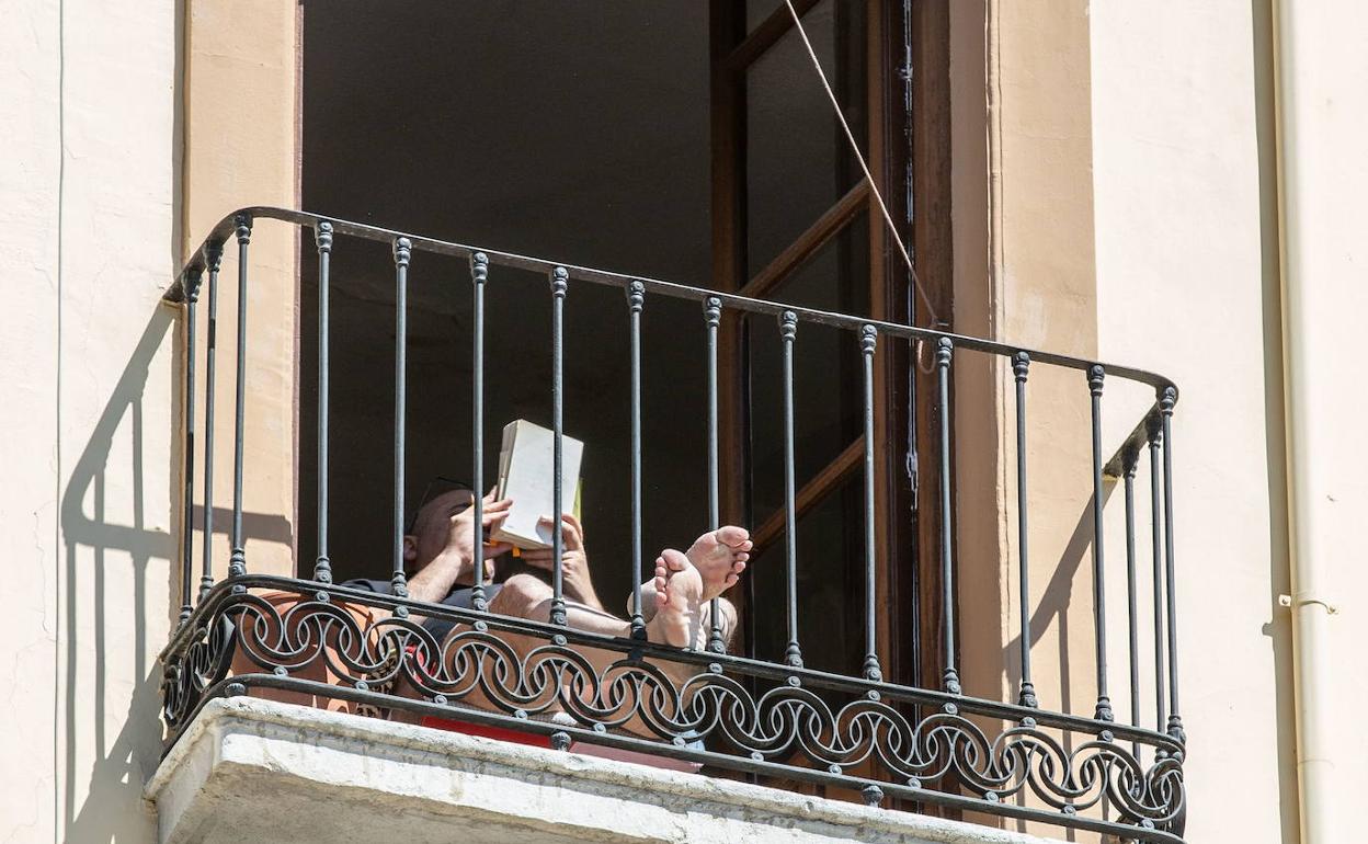 Un hombre lee en su balcón durante el confinamiento.