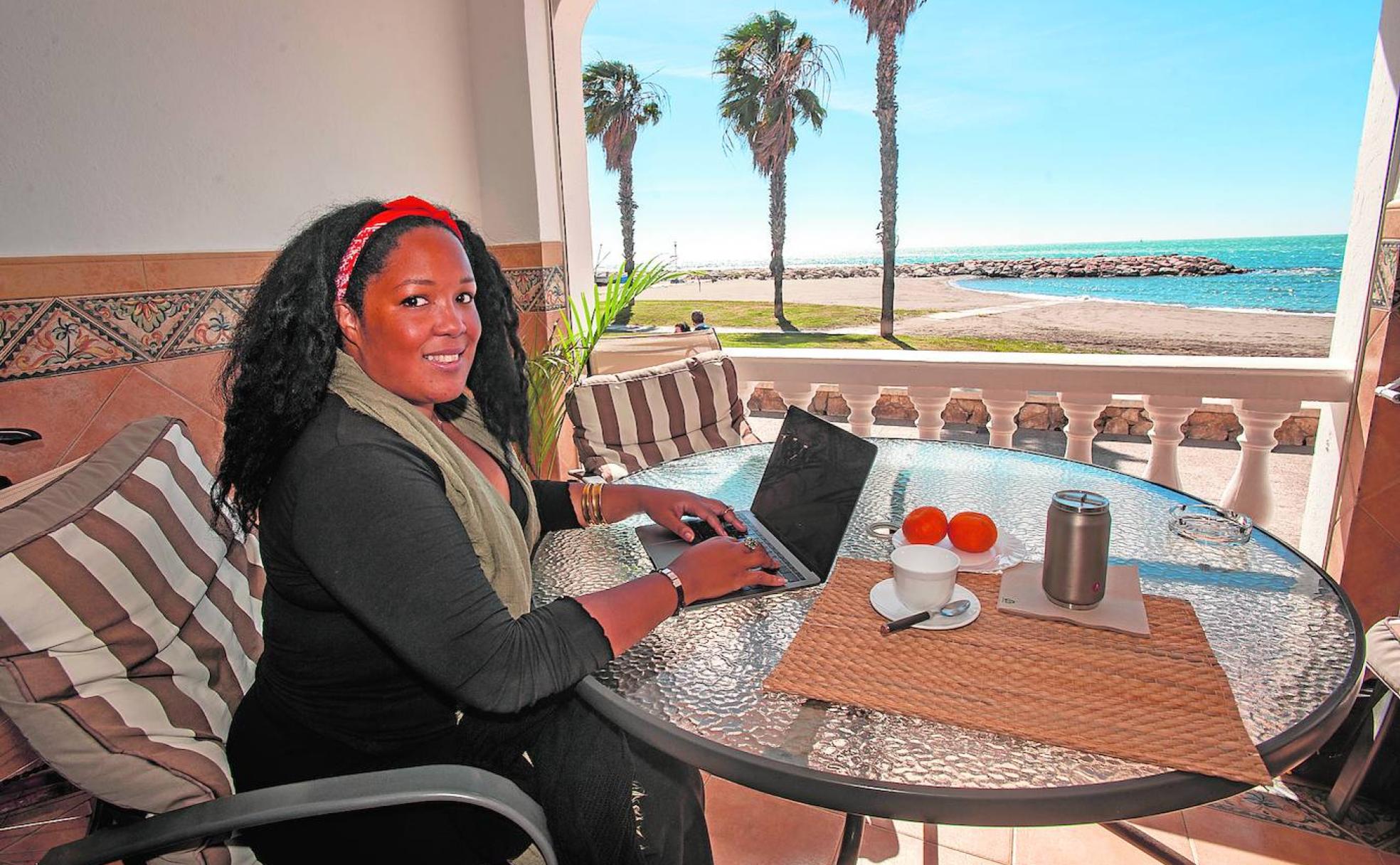 Melissa, jamaicana, trabajando con el ordenador portátil desde la terraza de una casa alquilada en la playa en Pedregalejo. 