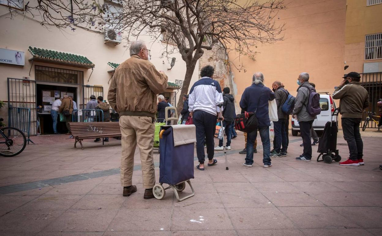 Colas de ciudadanos aguardando su turno para recoger comida en un comedor social de la capital