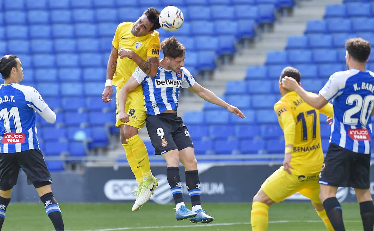 El jugador del Málaga, Alberto Escassi, gana un balón aéreo al delantero del Espanyol, Javier Puado.