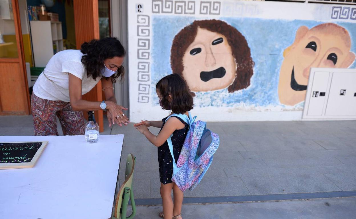 Una alumna se desinfecta las manos a la entrada de un colegio en Sevilla 