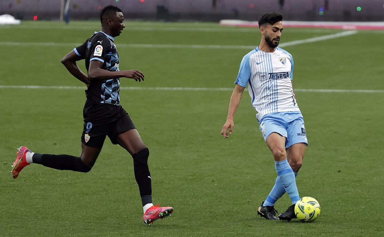 El jugador del Málaga, Juande Rivas, en un partido de la temporada pasada ante el Almeria en La Rosaleda. Le presiona el delatero Umar Sadiq.