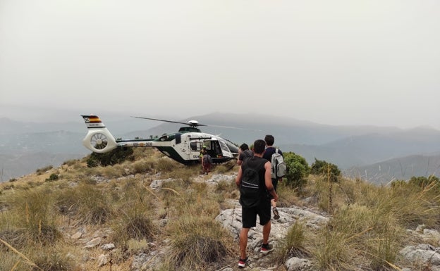 El helicóptero de la Guardia Civil, junto a los senderistas rescatados este domingo. 