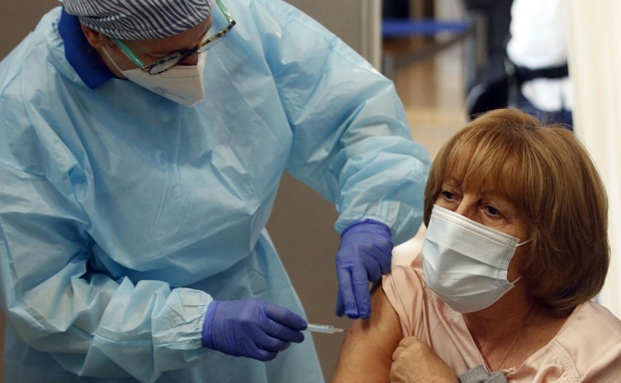 Momento en el que un sanitario administra la vacuna contra el coronavirus a una mujer. 