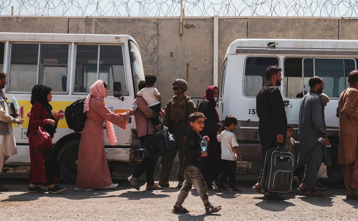 Varios ciudadanos tomas autobuses rumbo a los aviones en el aeropuerto de Kabul tras pasar los controles talibanes.