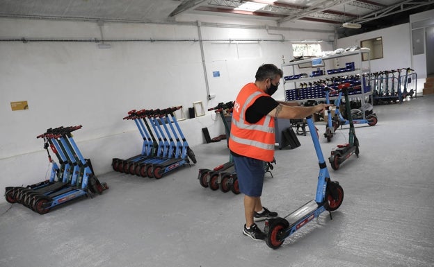 Imagen principal - En el almacén son puestos a punto los patinetes y se cargan las baterías para reponerlas. 