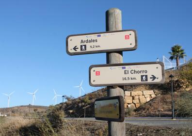 Imagen secundaria 1 - Los aerogeneradores forman parte del paisaje de esta ruta. Señales que indican el camino a seguir en el inicio. Descenso que hay que hacer al principio desde Carratraca.