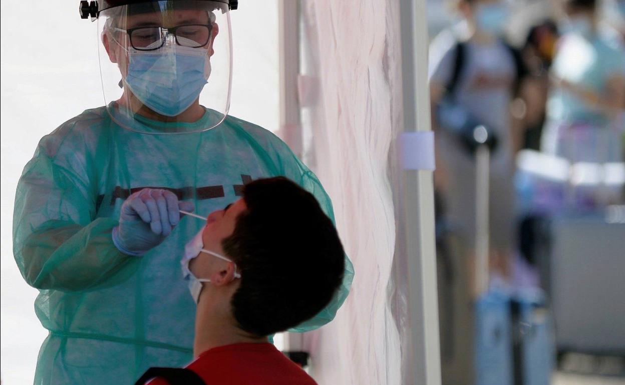 Un sanitario realiza una PCR a un joven. 