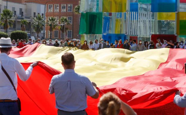 Miembros del PP de Málaga despliegan una gran bandera rojigualda en la explanada frente al cubo del Pompidou. 