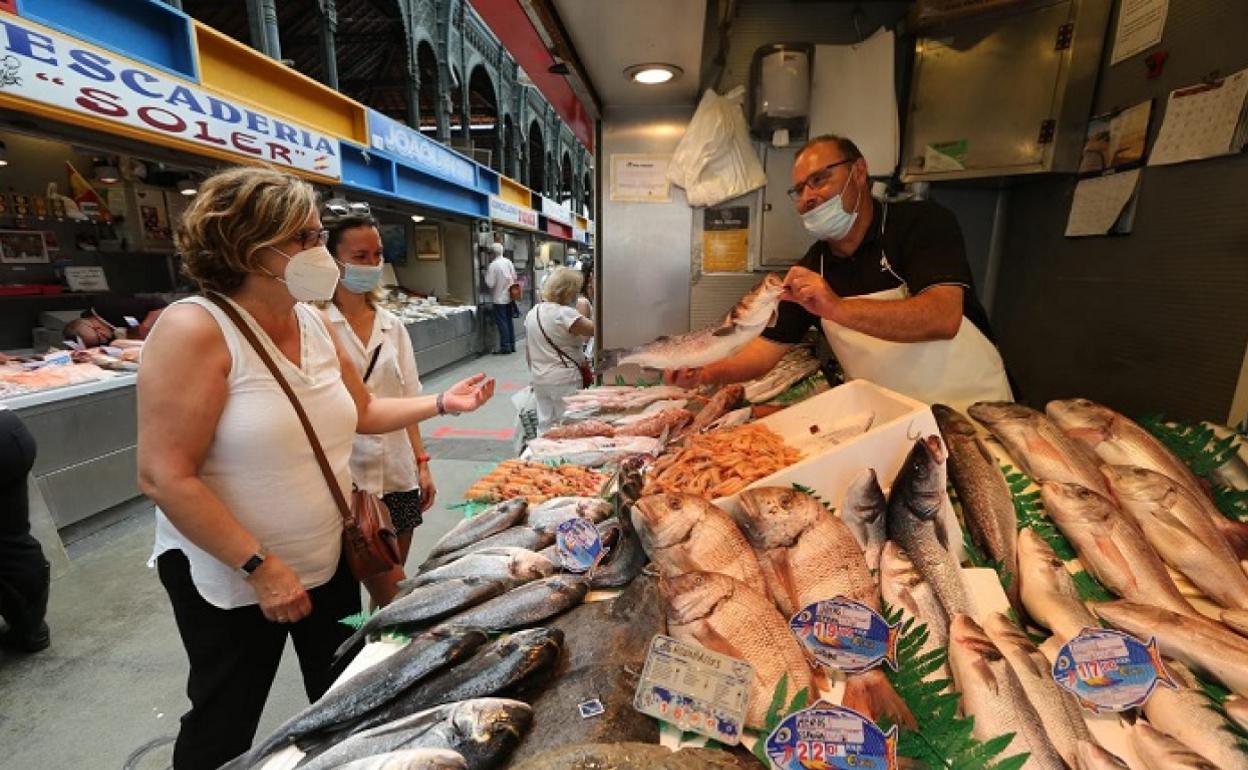 Un tendero en el Mercado de Atarazanas muestra el género a dos clientes. 