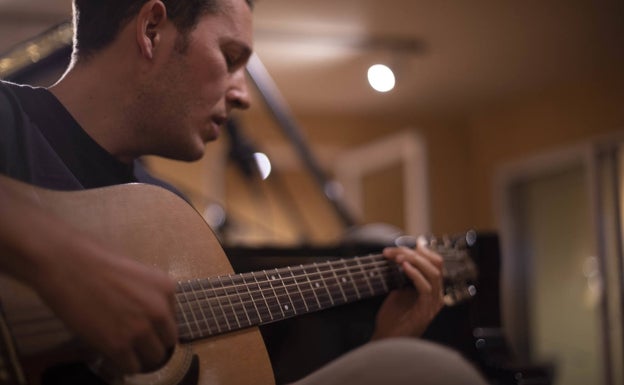 Imagen principal - Pablo Pareja, a la guitarra e interpretando un tema junto a la portada de su composición 'The Sea'.