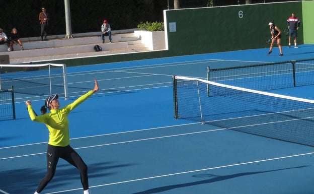 Un saque de Muguruza en una pista, con Badosa peloteando en la contigua, este martes. 