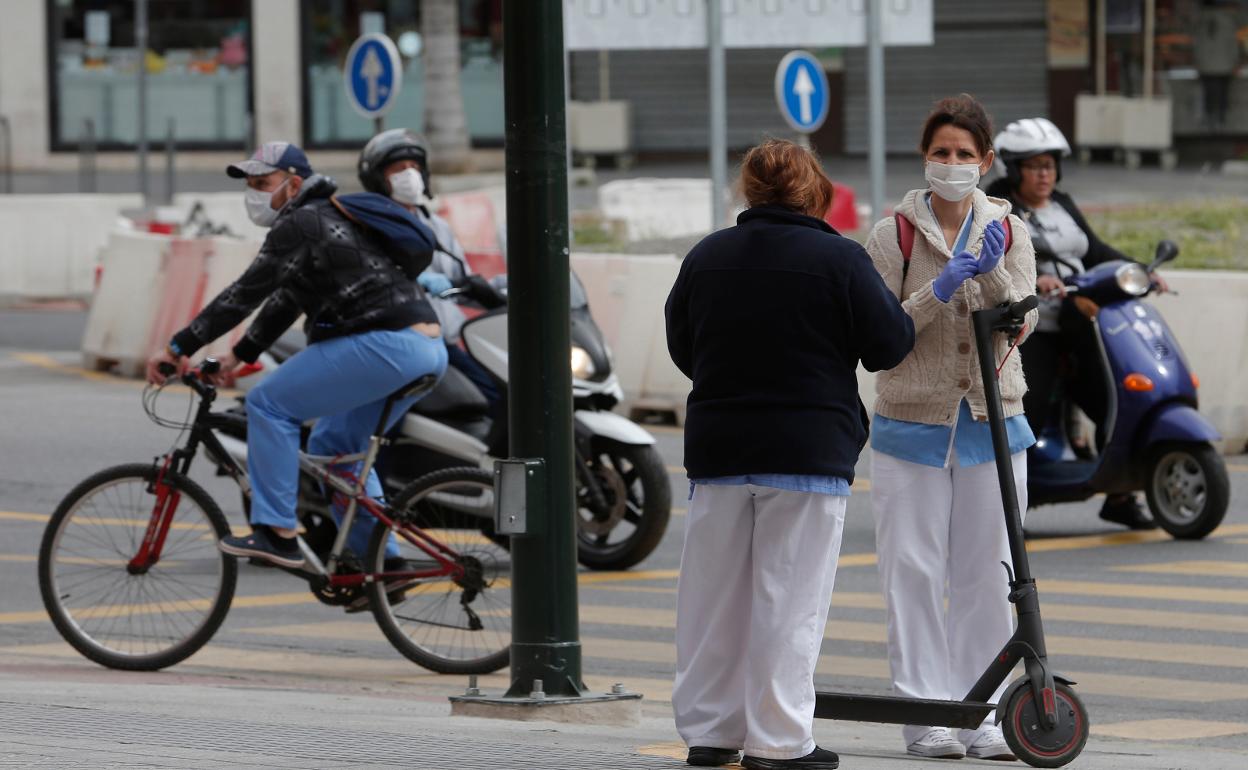 Varias personas circulan en distintos vehículos con las mascarillas puestas. 