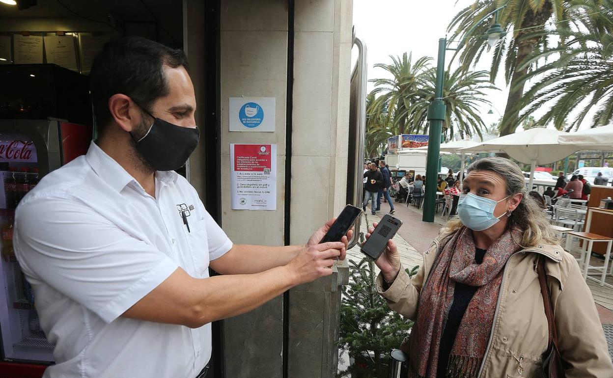 Un camarero de un bar de Málaga solicita el certificado Covid a una cliente. 