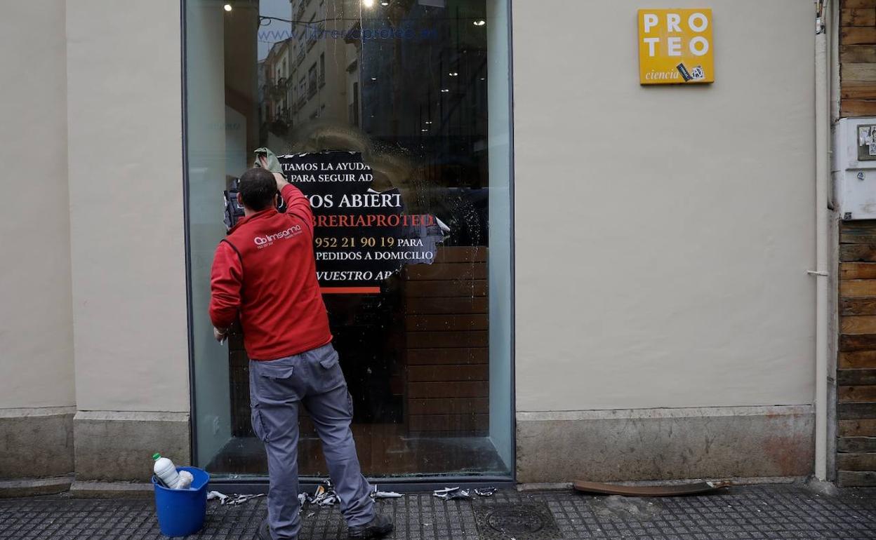 Un operario retiraba este martes el cartel que dirigía a los lectores al local cercano donde la librería ha abierto de forma temporal tras el incendio. 