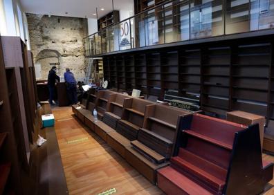 Imagen secundaria 1 - Arriba, el director de Proteo, Jesús Otaola, junto a los libros que han entrado ya en la restaurada sede de la librería. Abajo, la primera planta donde esta semana se rematan los últimos trabajos de la rehabilitación. A la derecha, detalle de la muralla de la ciudad en el interior del local que ha quedado oscurecida por el fuego del pasado mes de mayo. 