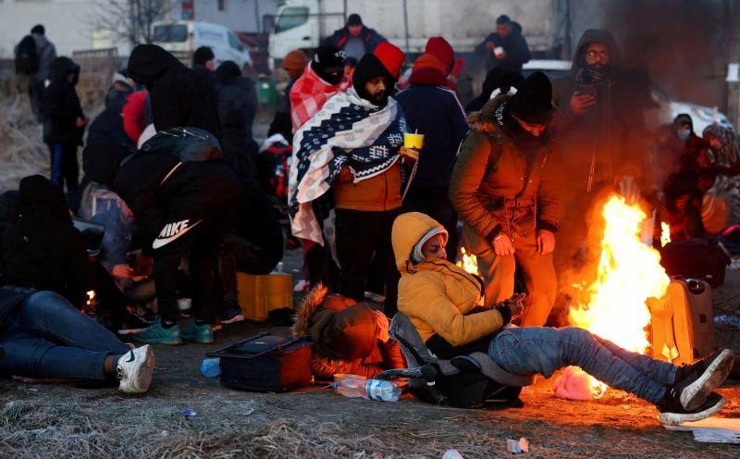 Un grupo de refugiados se calienta en una hoguera en la frontera con Polonia.