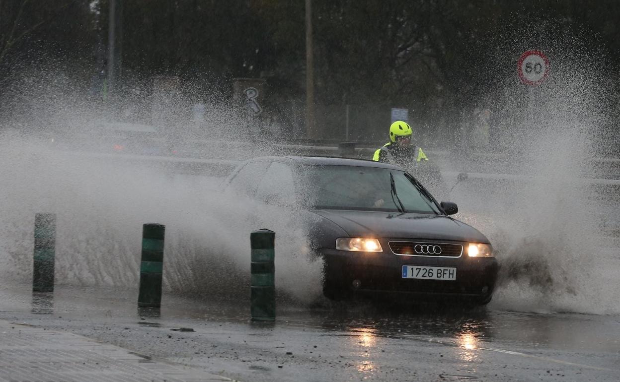 Un coche pasa sobre un charco en la capital malagueña. 