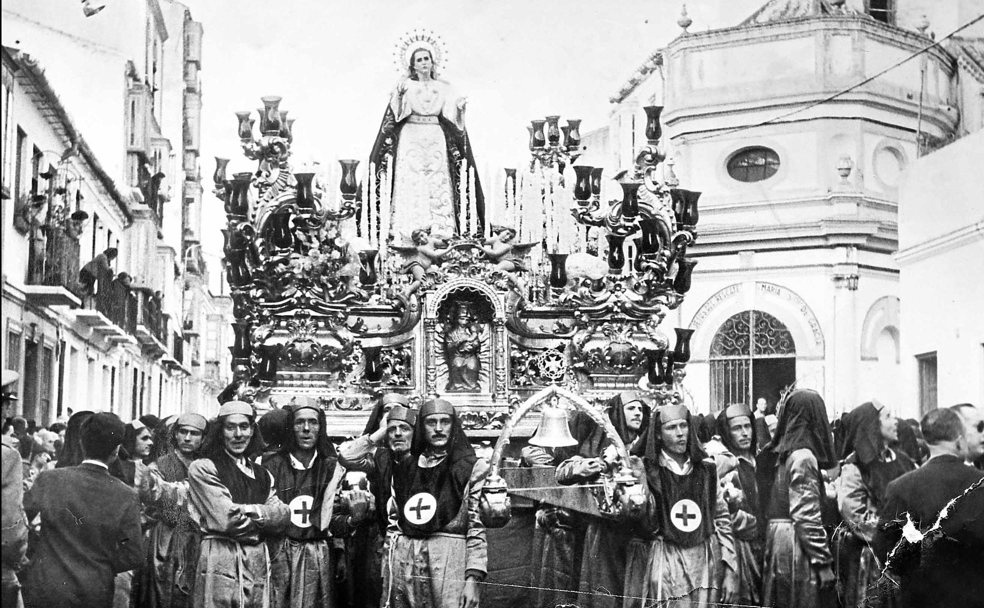 1960. El trono de la Virgen de Gracia, obra de Pedro Pérez Hidalgo, enfila la calle Victoria para iniciar su salida procesional. 