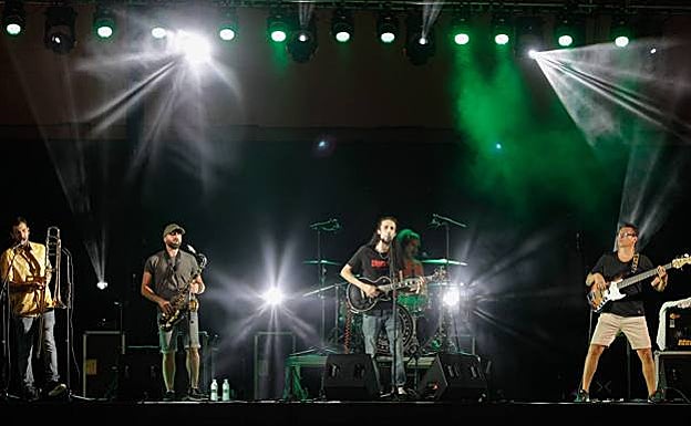 Imagen principal - Jammín' Dose y Julia Martín, junto al cartel del concierto del 20 aniversario de Doctor Aliñao. 