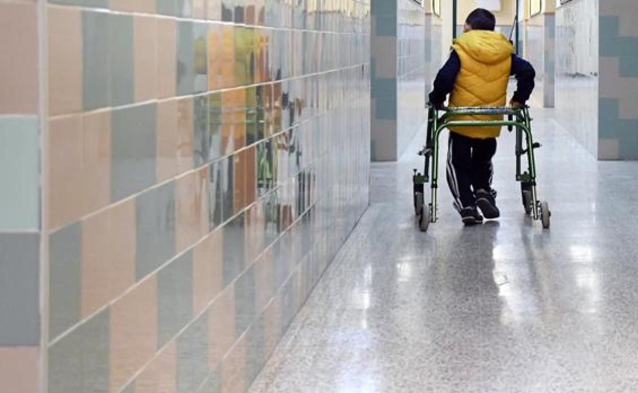 Un niño con discapacidad camina por el pasillo de un colegio. 