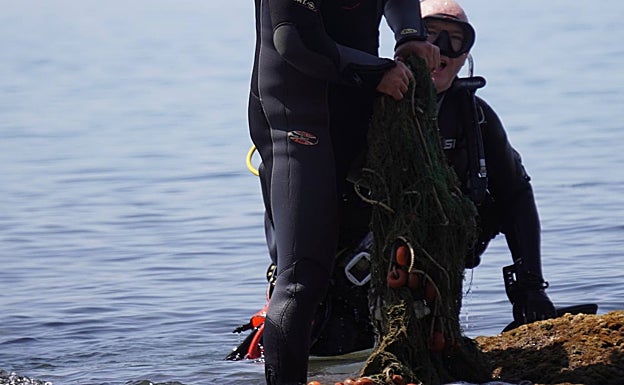 Buceadores, en el momento de sacar a la superficie uno de los trozos de red. 