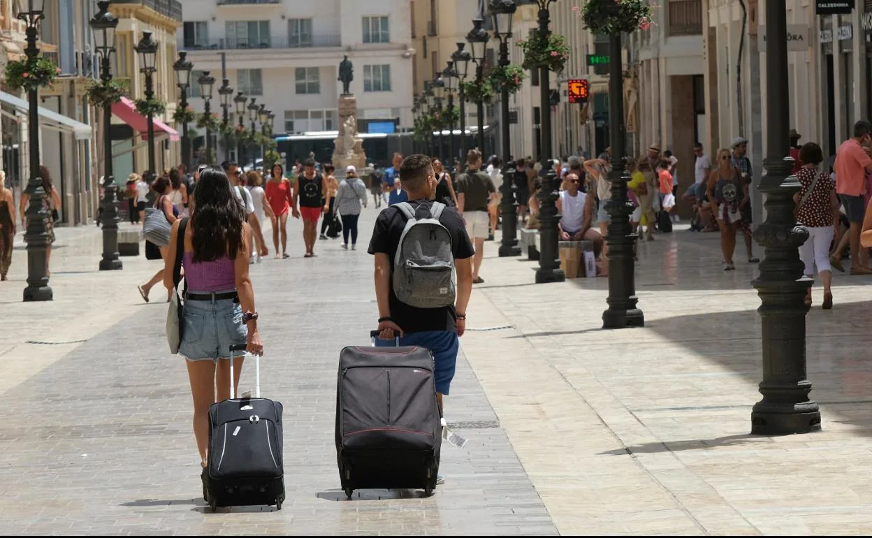 Turistas, con sus maletas, se desplazan por la calle principal del Centro Histórico de Málaga. 