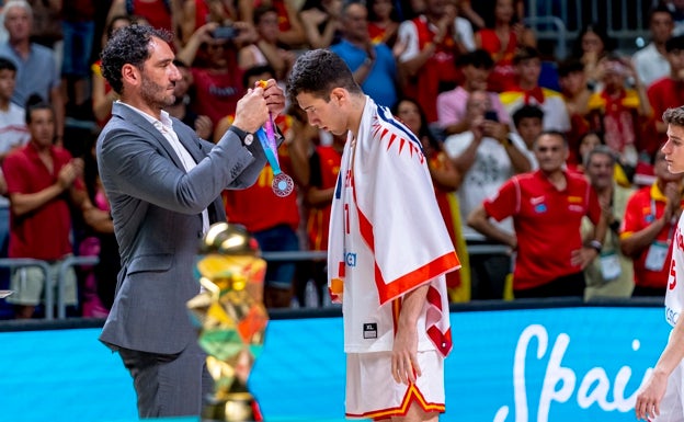 Folgueiras, con la bandera del C.B. El Palo recibe la medalla de plata de Jorge Garbajosa. 