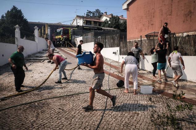 Vecinos de Canecas, a las afueras de Lisboa, se organizan para combatir el fuego.