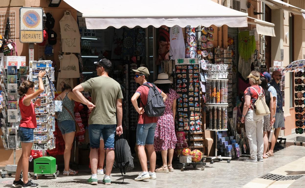 Turistas buscan un recuerdo de su estancia en la capital de la Costa del Sol en una tienda del Centro. 