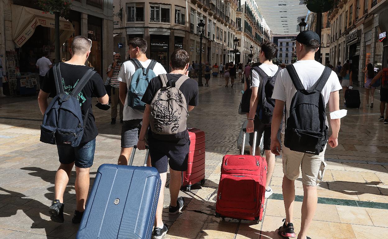 Un grupo de turistas se dirige hacia sus alojamientos por la calle Larios, arteria principal de la ciudad. 