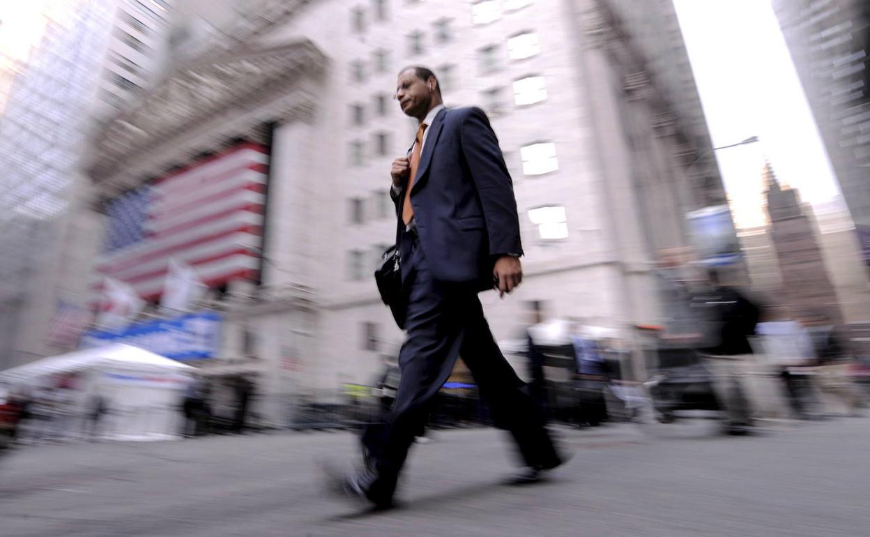 Un ciudadano camina frente a la fachada de Wall Street. 