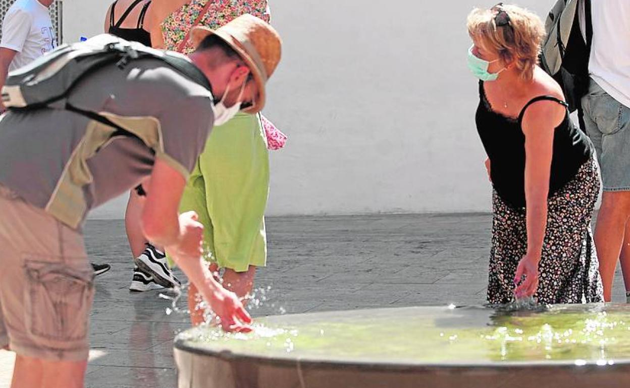 Turistas se refrescan en una fuente en el Centro de Málaga. 