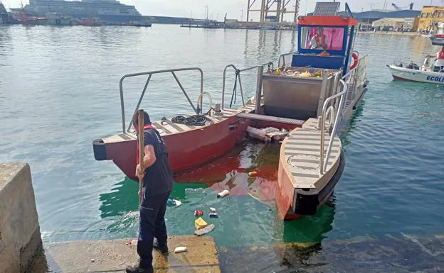 El marinero, Pablo Martín, empuja los residuos al interior del barco 'pelican'. 