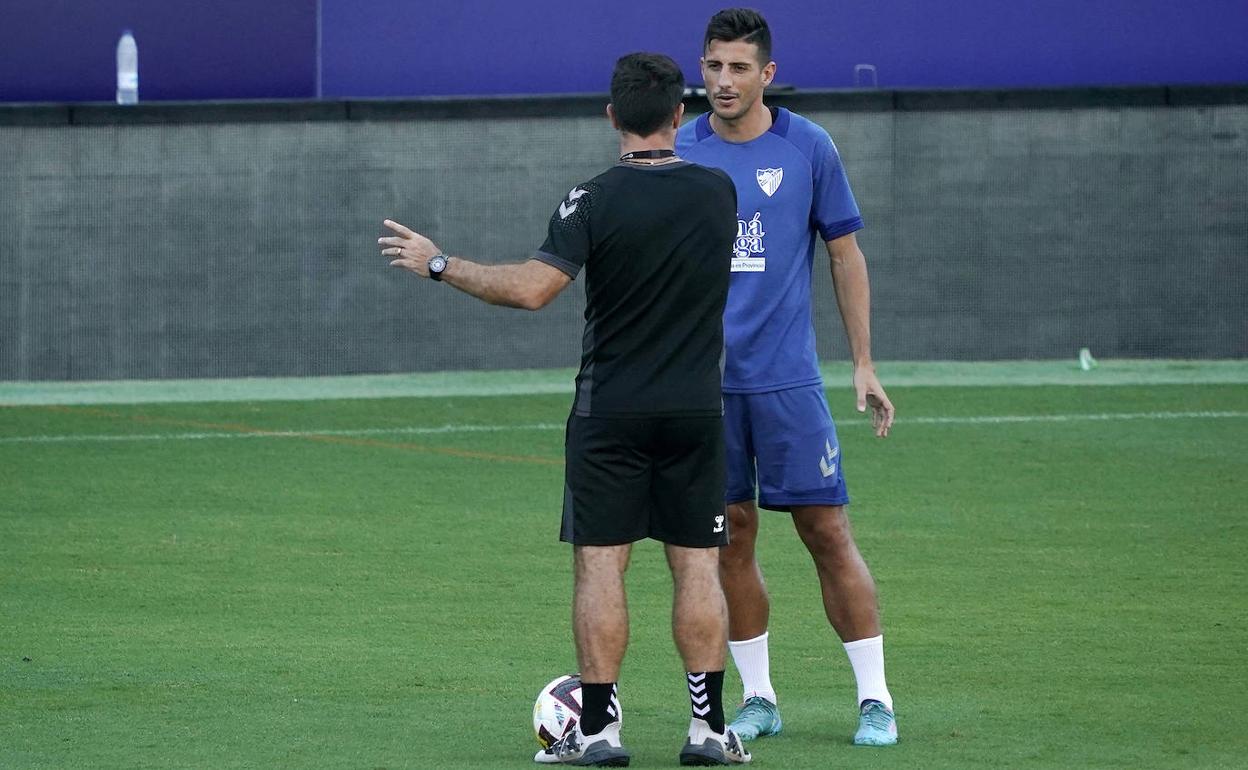 El futbolista Pablo Chavarría y el entrenador Pablo Guede (de espalda) charlan días atrás durante un entrenamiento del Málaga.