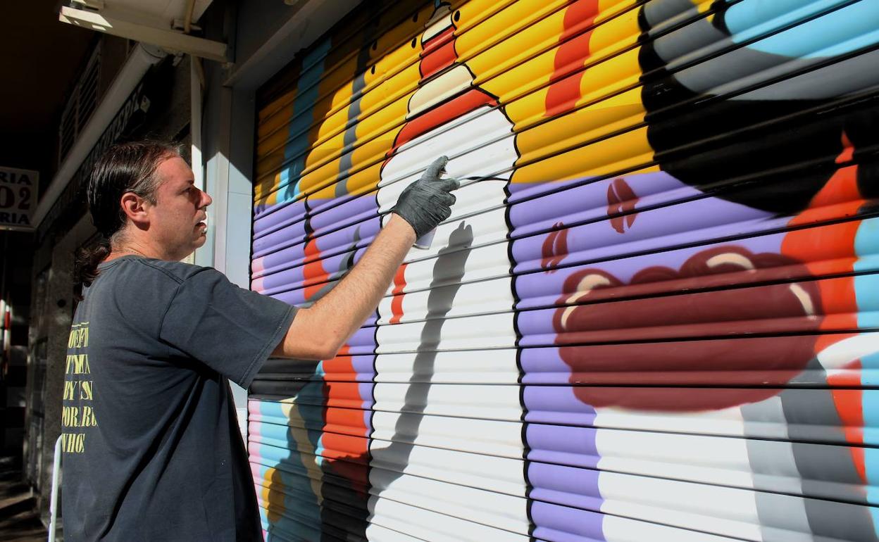 El muralista Francisco Javier Dólera trabajando en una de las persianas como parte del proyecto 'Color en el barrio'. 