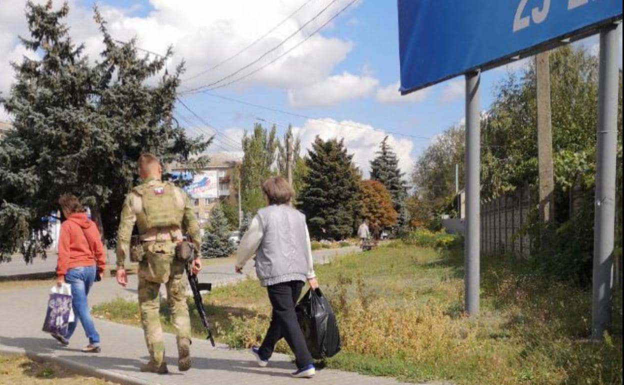 Un soldado ruso acompaña a dos civiles a un punto de votación durante los referéndums para la anexión de los territorios ocupados a Rusia.