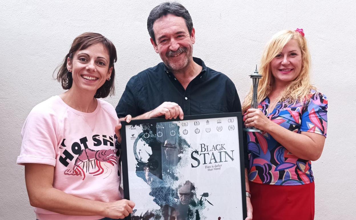 Isa Sánchez, Enrique García y Natalia Roig, con el cartel de la versión inglesa de 'La mancha negra', tras conocer los premios en Seattle.