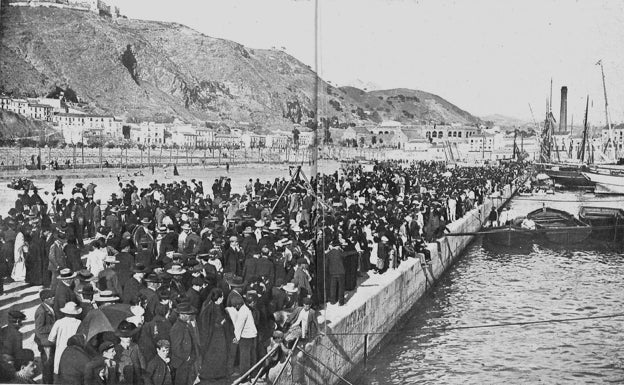 Imagen principal - Arriba, uno de los buques, antes de zarpar del puerto de Málaga; abajo, a la izquierda, una de las familias que emigraron, fotografiada en Hawái, y a la derecha, cartel del congreso internacional de Cáceres. 