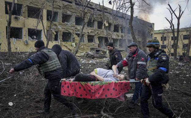 Imagen principal - Arriba, sanitarios evacúan a una embarazada después de que Rusia bombardease una maternidad en Mariúpol, en marzo. Abajo a la izquierda, un miembro del batallón Azov durante el asedio por parte de las tropas invasoras de la acería Azovstal, que duró semanas. Abajo a la derecha, imagen aérea de la destrucción de Mariúpol, que antes de la guerra contaba con medio millón de habitantes.