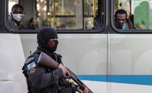 Dos pasajeros de un autobus observan a un policía durante una protesta en Río de Janeiro.