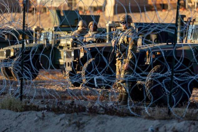 Soldados de la Guardia Nacional de Texas montan guardia detrás de una concertina en la frontera entre Estados Unidos y México el 21 de diciembre de 2022, visto desde Ciudad Juárez, México.